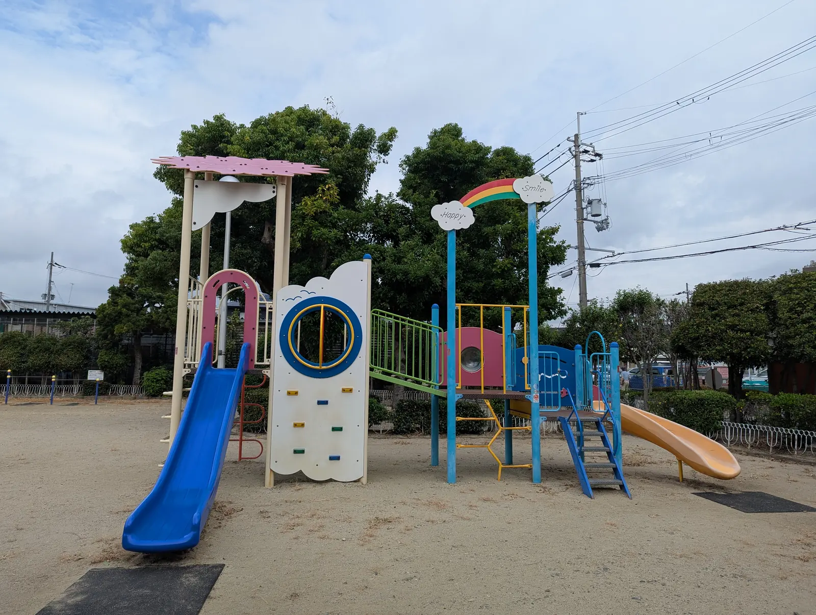 虹色の飾りと二つのすべり台が付いた北伊丹第一公園の複合遊具